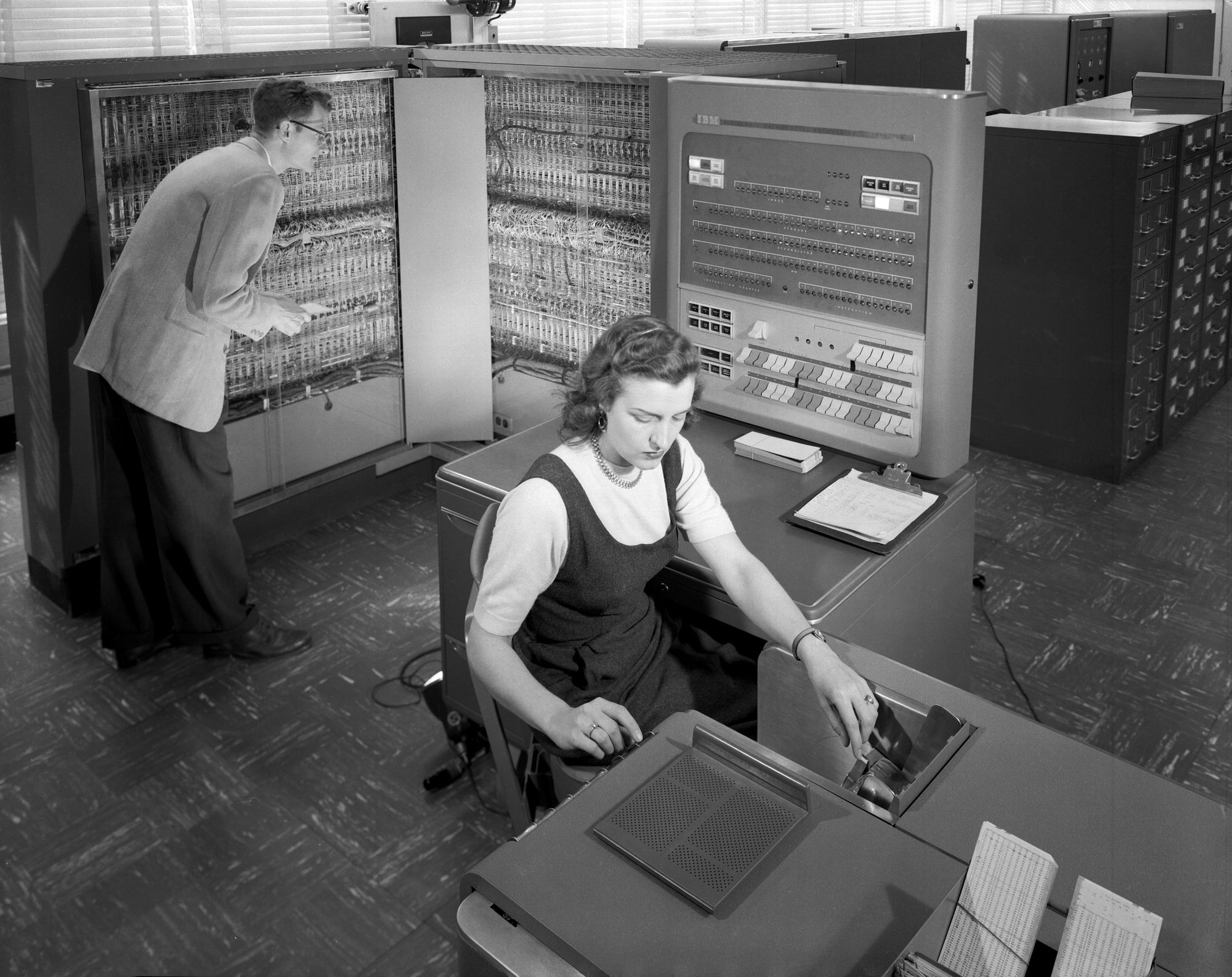 Picture of a man and a woman operating the IBM 704 in 1957.